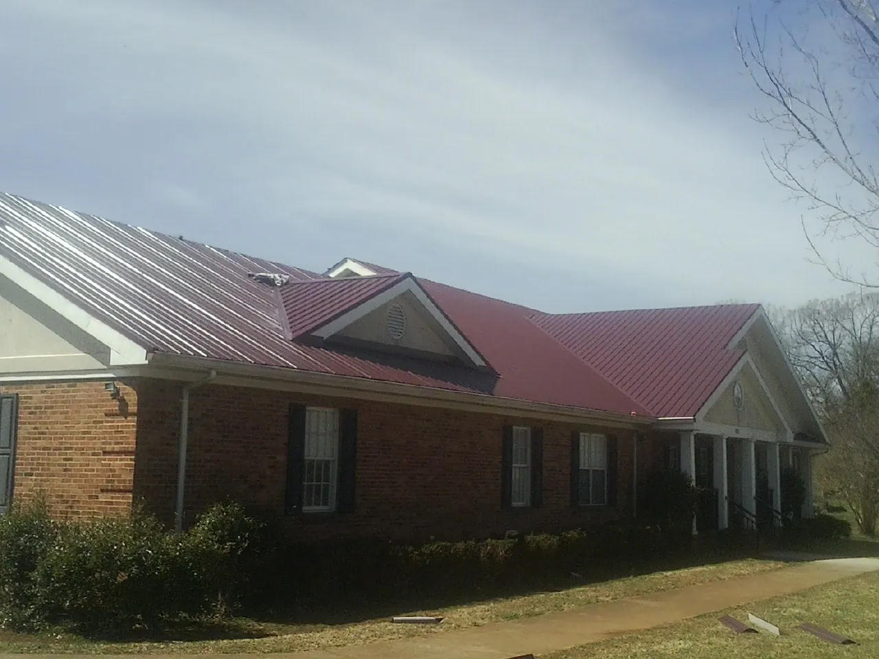 Red metal roof with gabled entries on a long brick building in Sycamore