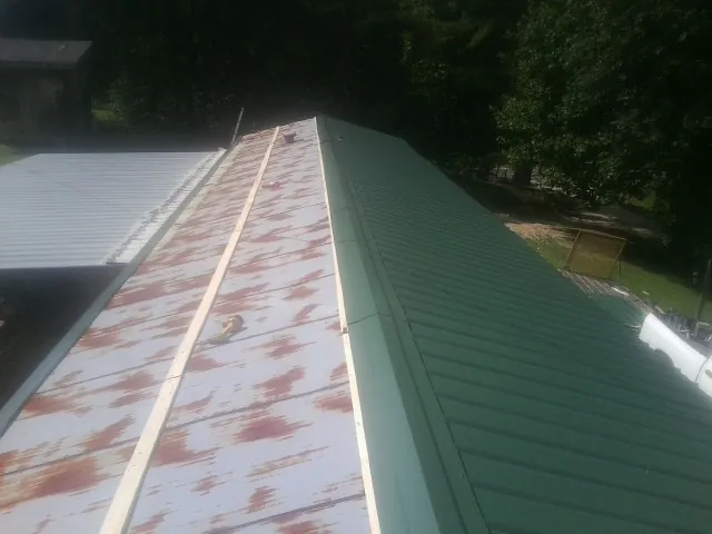 Old rusted panels beside newly installed green metal roofing — Wind Damage Roof Repair by Roofing Brothers in Sycamore