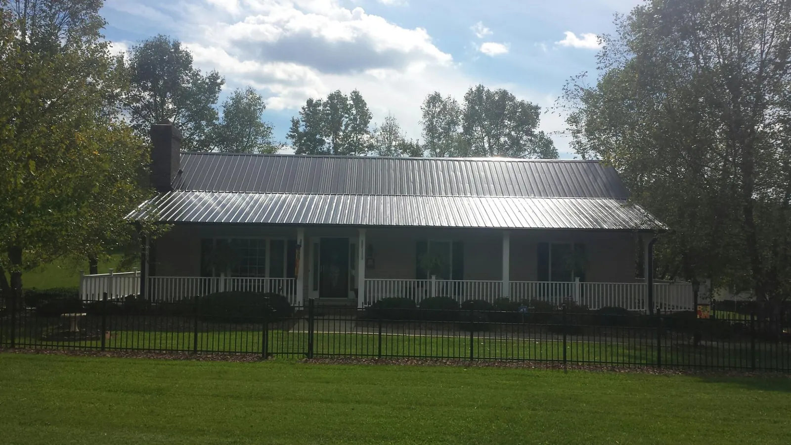 Gray metal roof on a brick ranch with a full width front porch — Gutter Guard Installation work by our crew in Sycamore